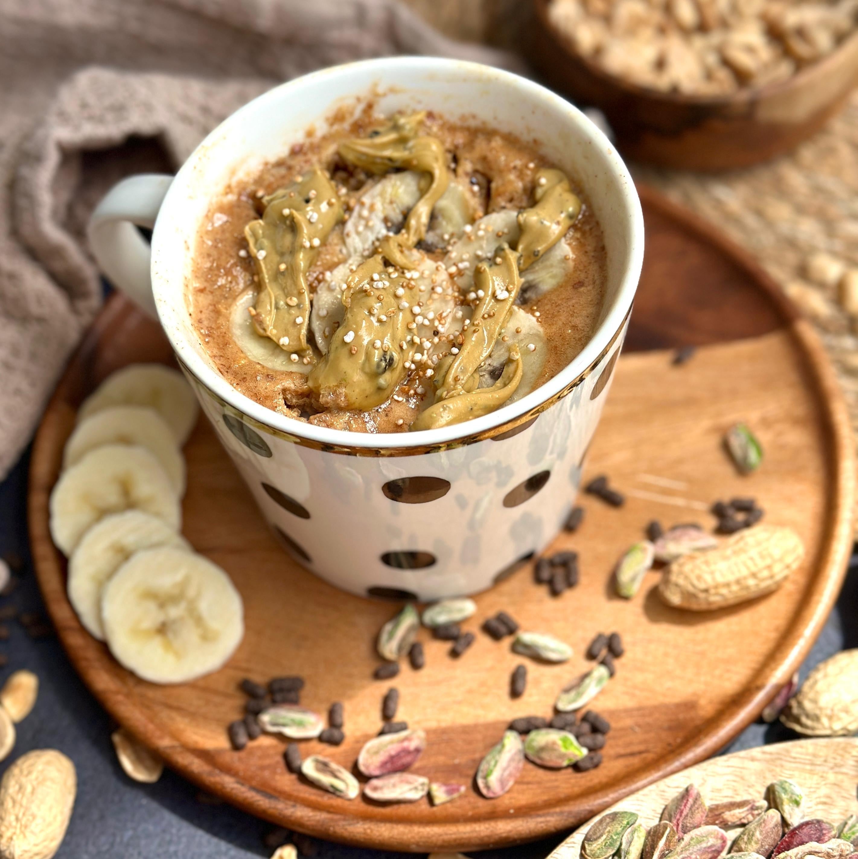 Proteinreicher Bananenbrot Tassenkuchen mit cremiger Gain Kitchen Pistaziencreme als Topping, angerichtet in einer Tasse – gesunder, zuckerfreier Snack für schnelle Zubereitung und langanhaltende Energie.