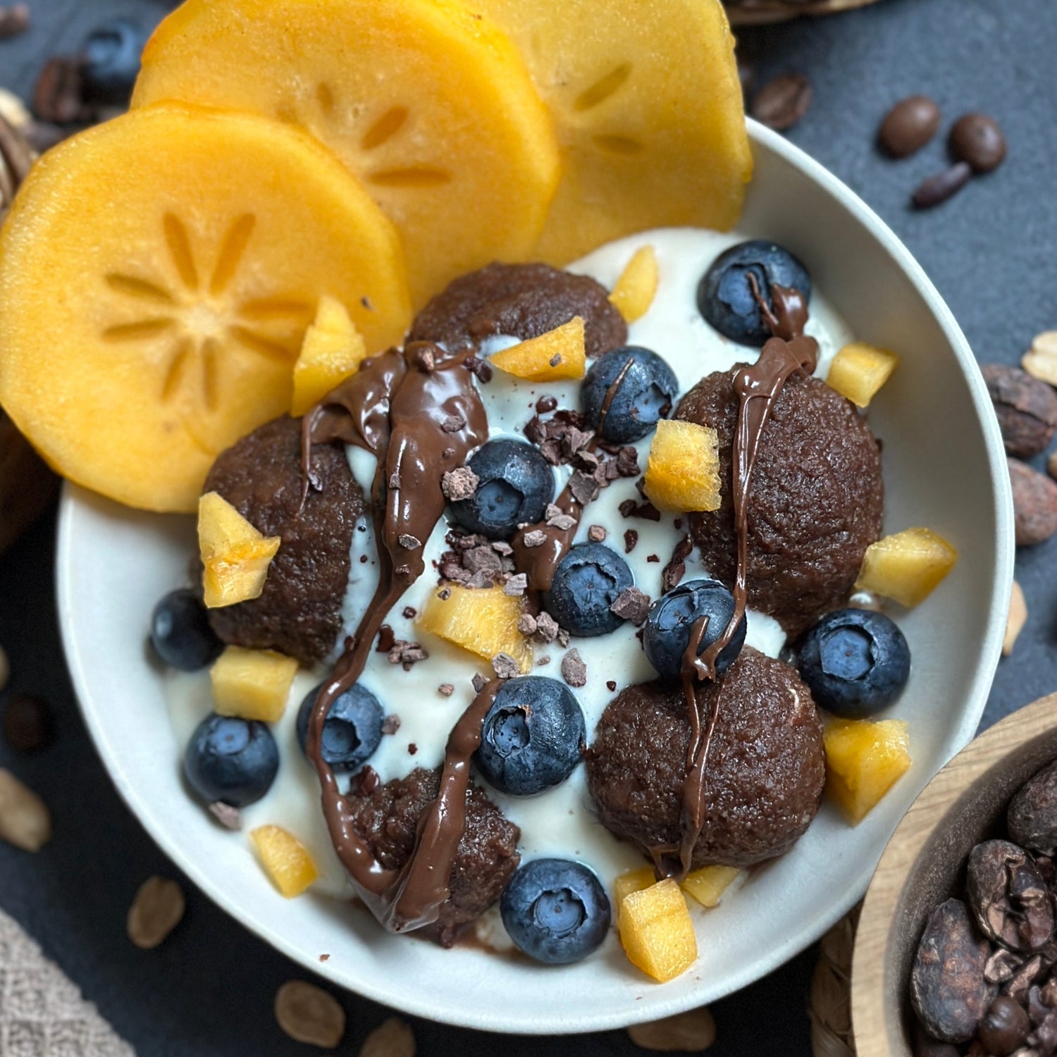 Schoko Kartoffelklöße in einer Bowl, getoppt mit Vanillecreme, frischem Obst und dunklem Protein-Spread.