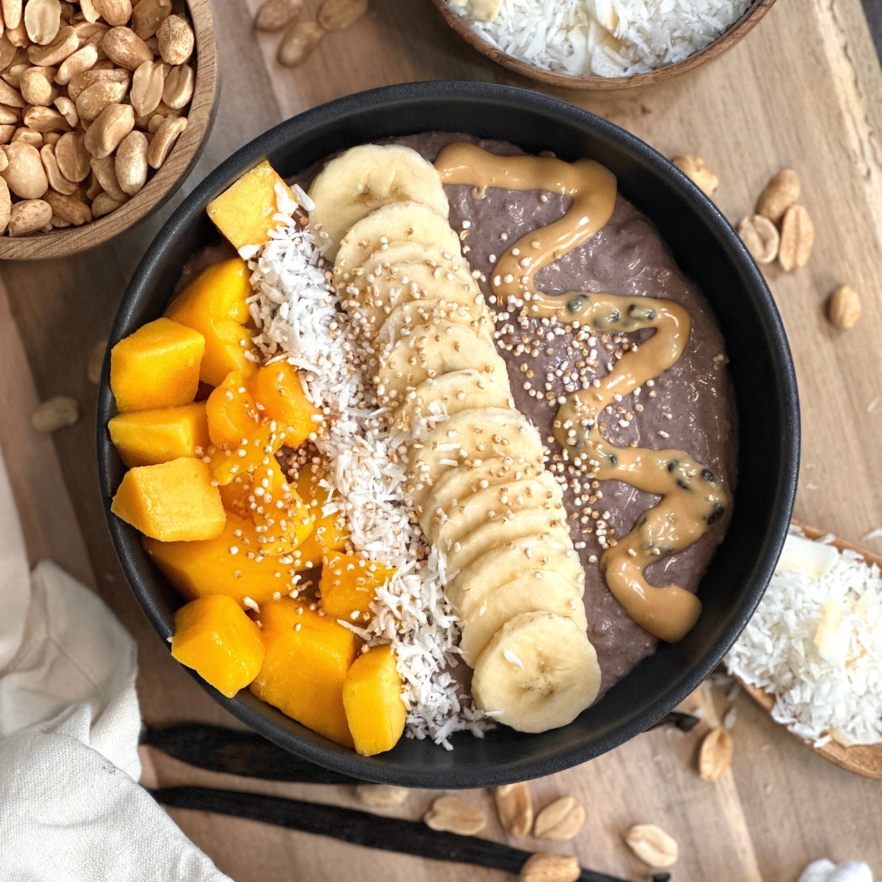 Tropische Acai-Joghurtbowl mit Mango, Banane, Kokosraspeln und cremigem Acai-Protein-Topping in einer Schüssel.