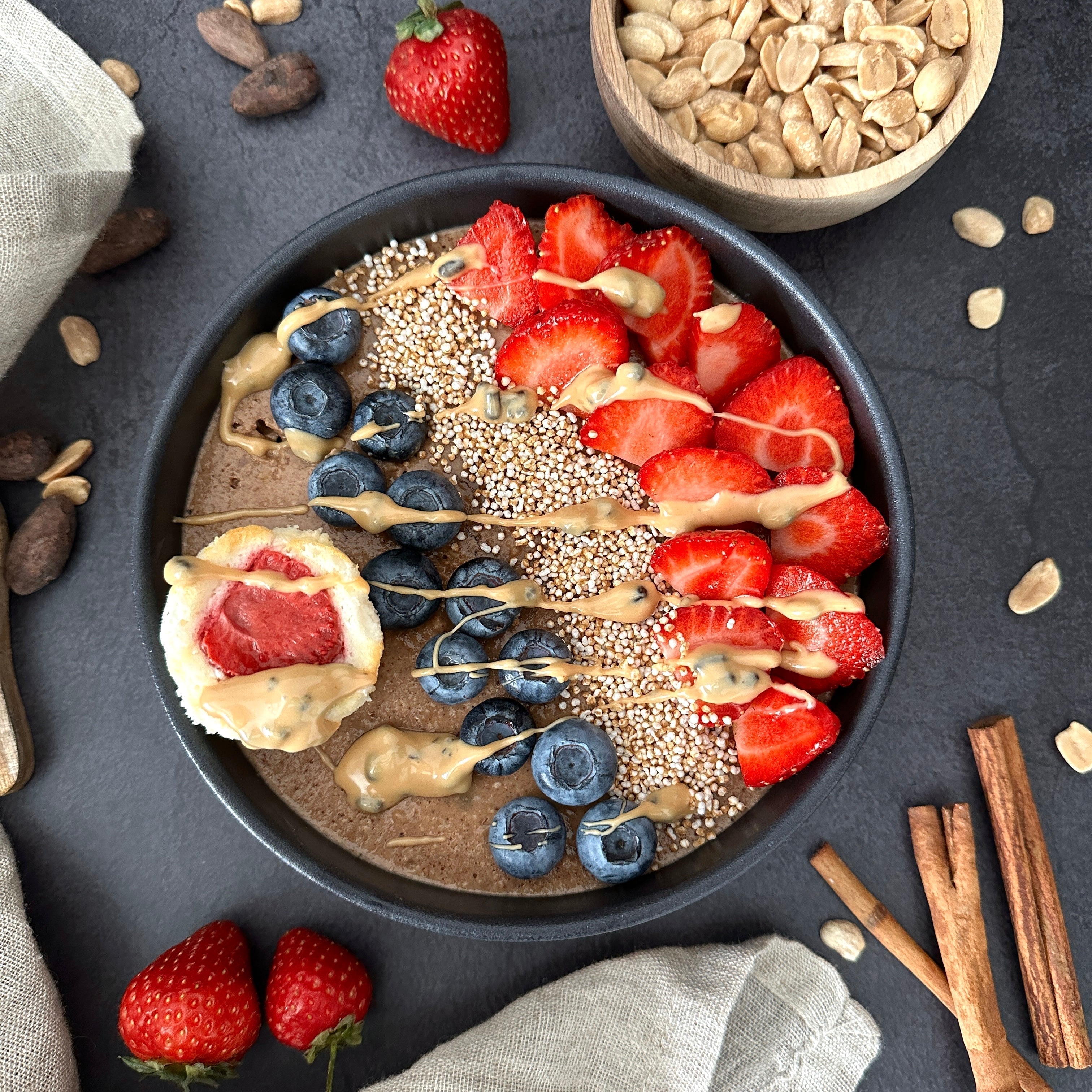 Warme zimtige Haferflockenbowl mit frischen Beeren und cremigem Zimt-Protein-Spread als Topping.