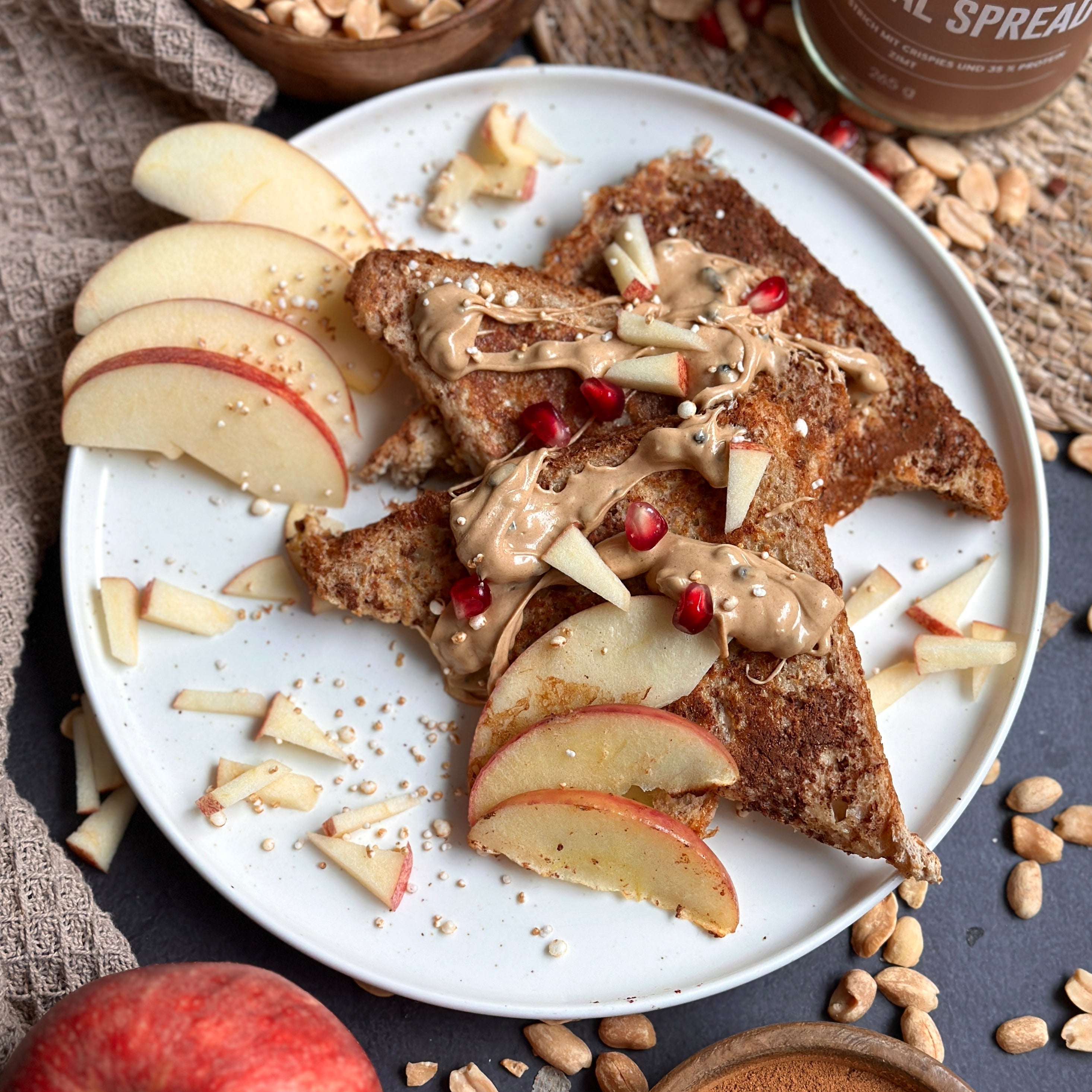 Zimtige Frenchtoasts mit Apfelscheiben und cremigem Protein Spread als Topping auf einem Frühstücksteller.