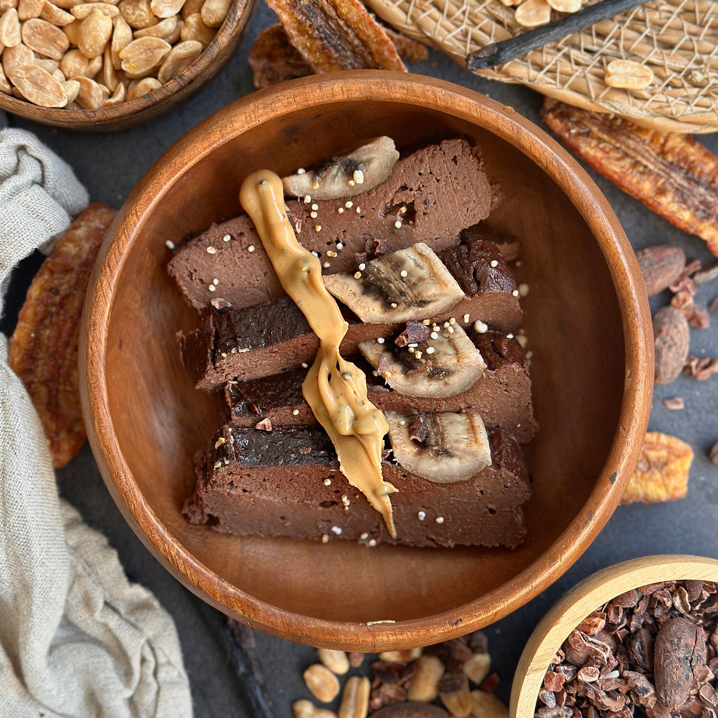  Saftiges Schoko-Protein-Bananenbrot mit Banane und Vanillecreme serviert auf einem Holzbrett.