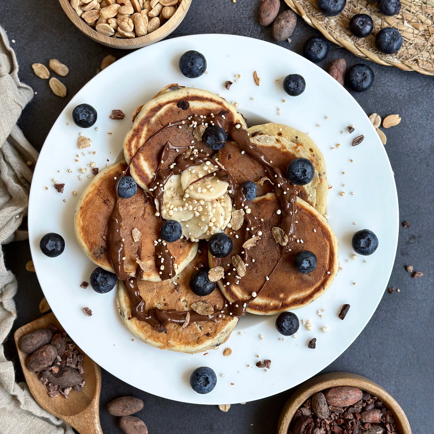  Fluffige Chocolate-Chip Protein Pancakes auf einem Teller, garniert mit Schoko-Protein-Spread und frischen Beeren.