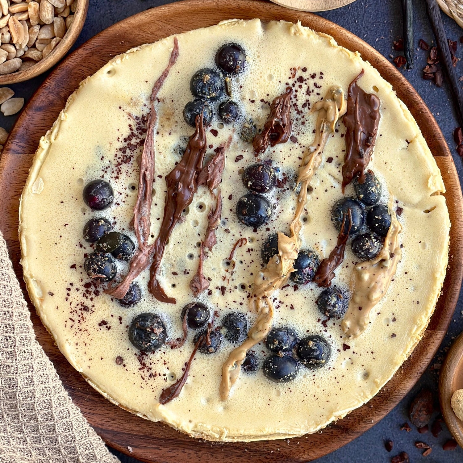 High Protein Crêpe mit frischen Blaubeeren und cremigem Gain Kitchen Protein Spread, garniert mit Kürbiskernen und Rohkakao.