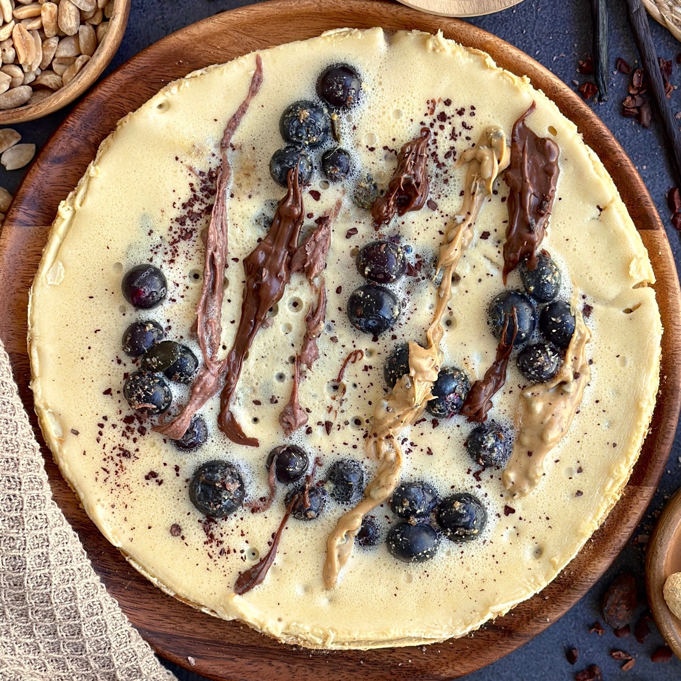High Protein Crêpe mit frischen Blaubeeren und cremigem Gain Kitchen Protein Spread, garniert mit Kürbiskernen und Rohkakao.