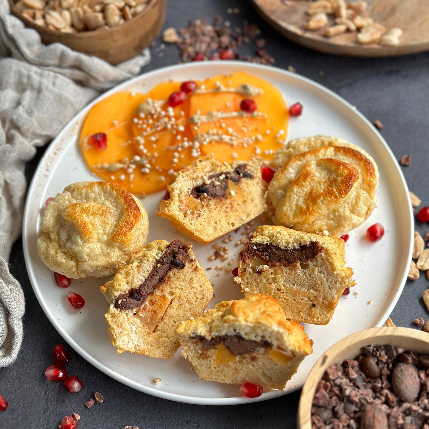 Low Carb Kaki-Cheesecake Muffins auf einem Holzbrett, gefüllt mit cremigem Schoko-Protein-Spread und frischer Kaki.