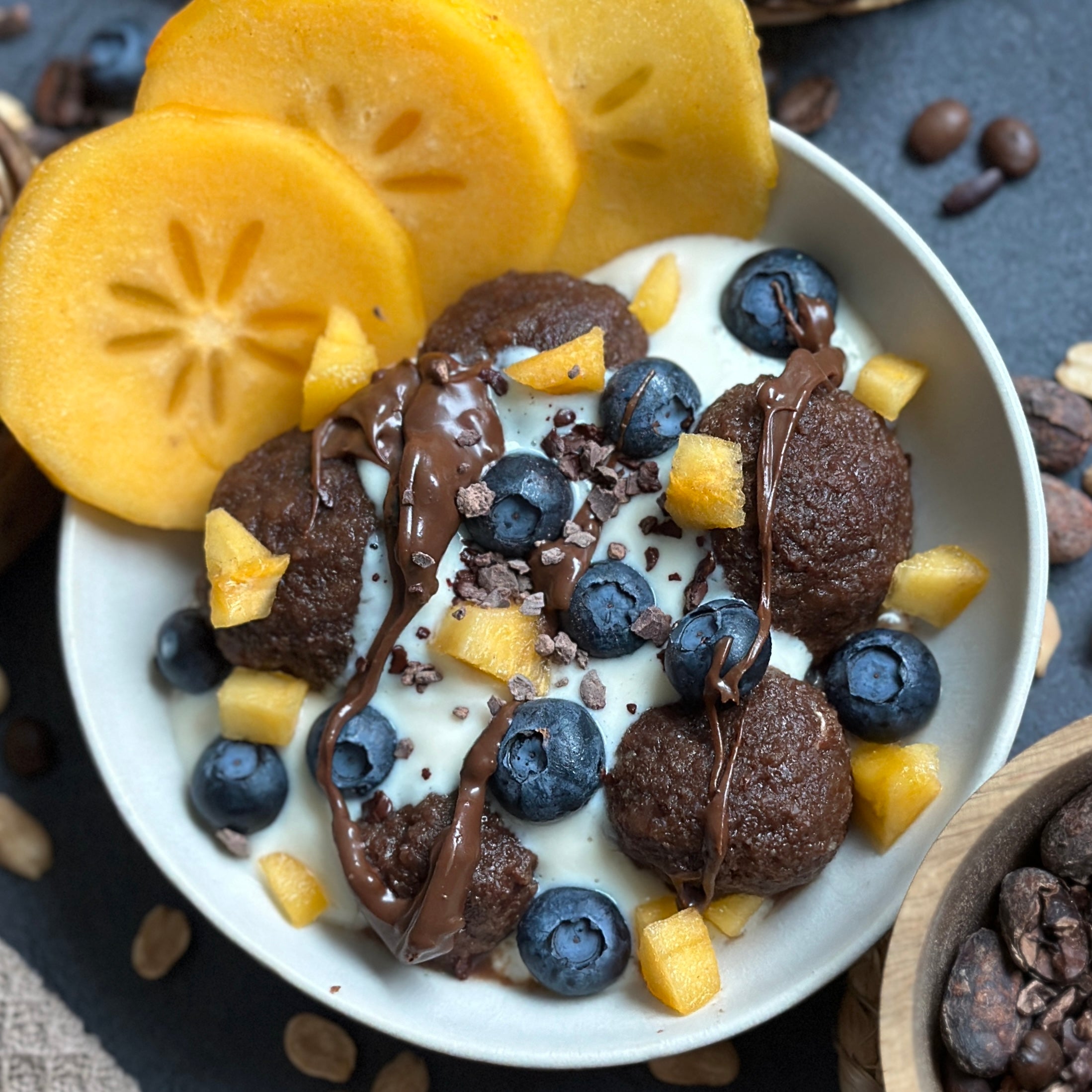 Schoko Kartoffelklöße in einer Bowl, getoppt mit Vanillecreme, frischem Obst und dunklem Protein-Spread.