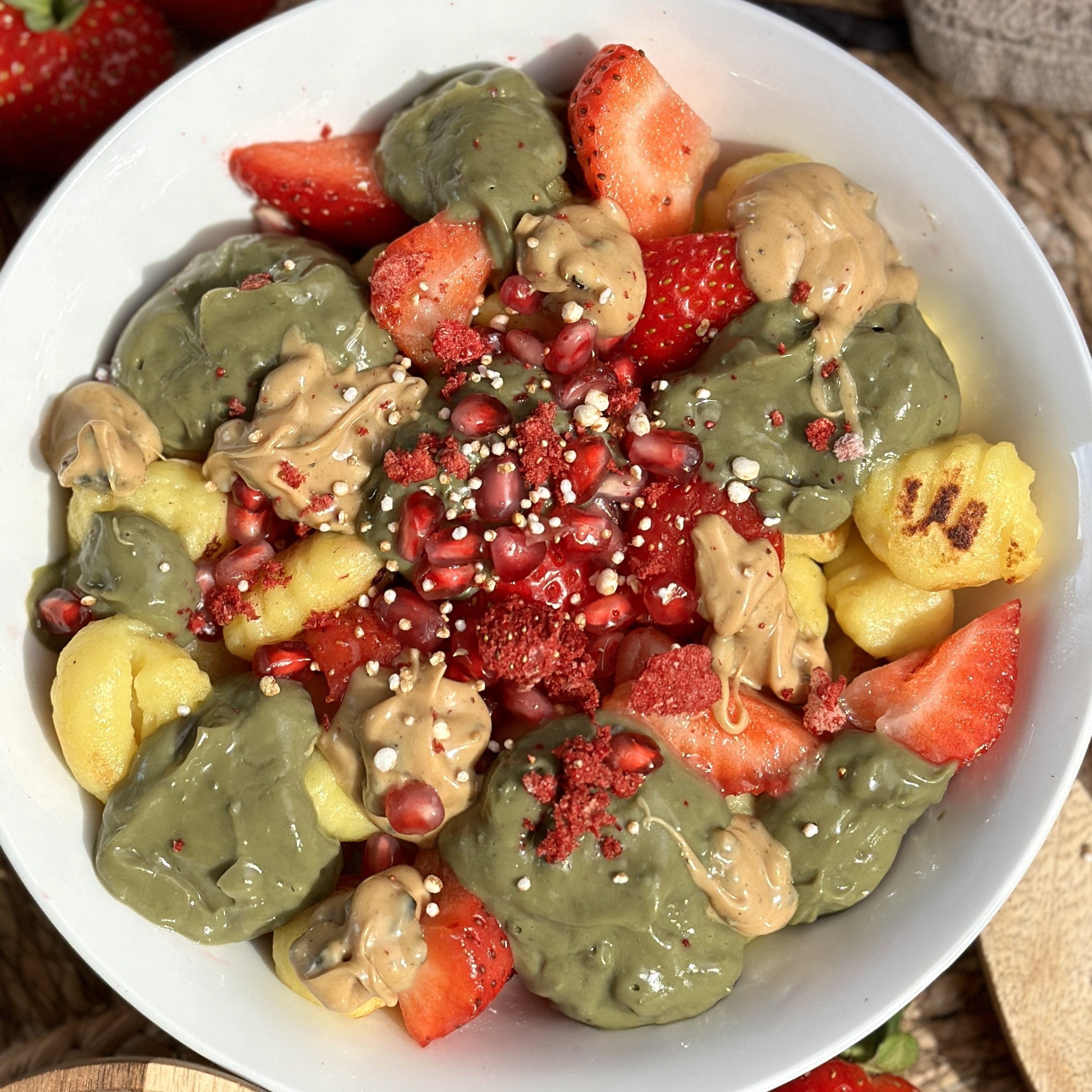 Grün-goldbraun gebratene Matcha-Gnocchi in einer Schale, getoppt mit cremigem Vanille Spread, frischen Erdbeeren und gepufftem Quinoa.