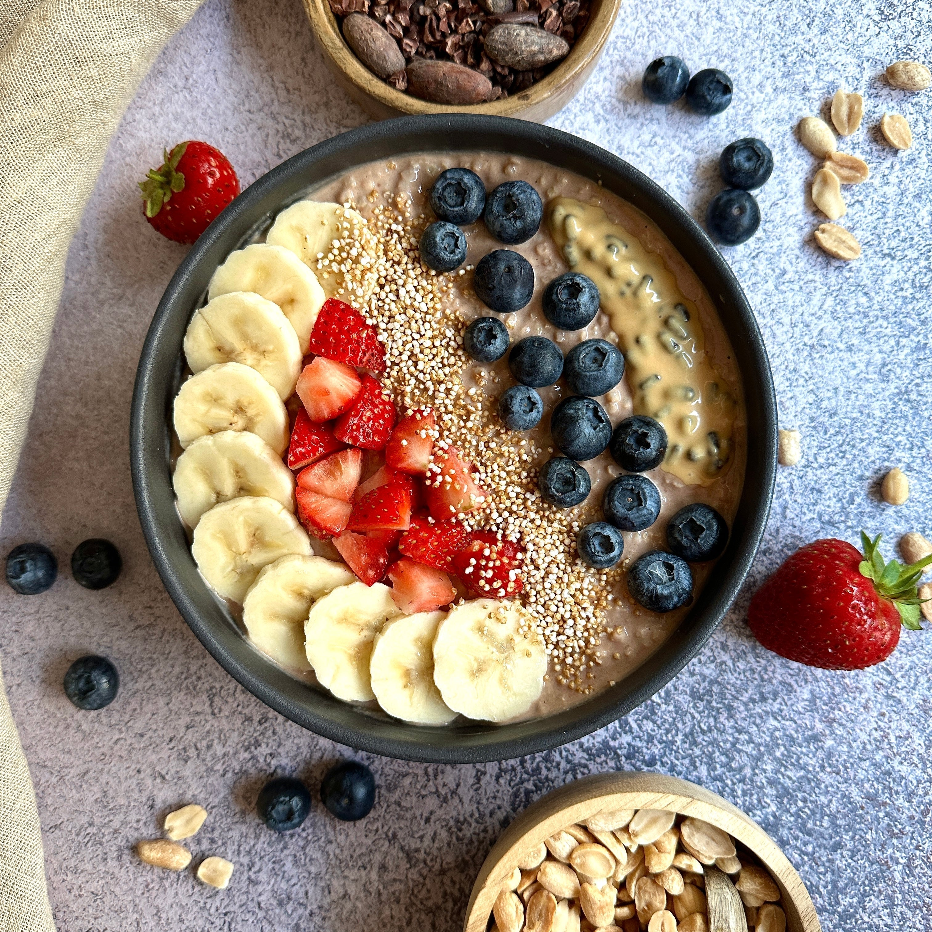 Schoko-Hirse Porridge in einer Schale, getoppt mit Protein-Spread, Banane und Beeren.