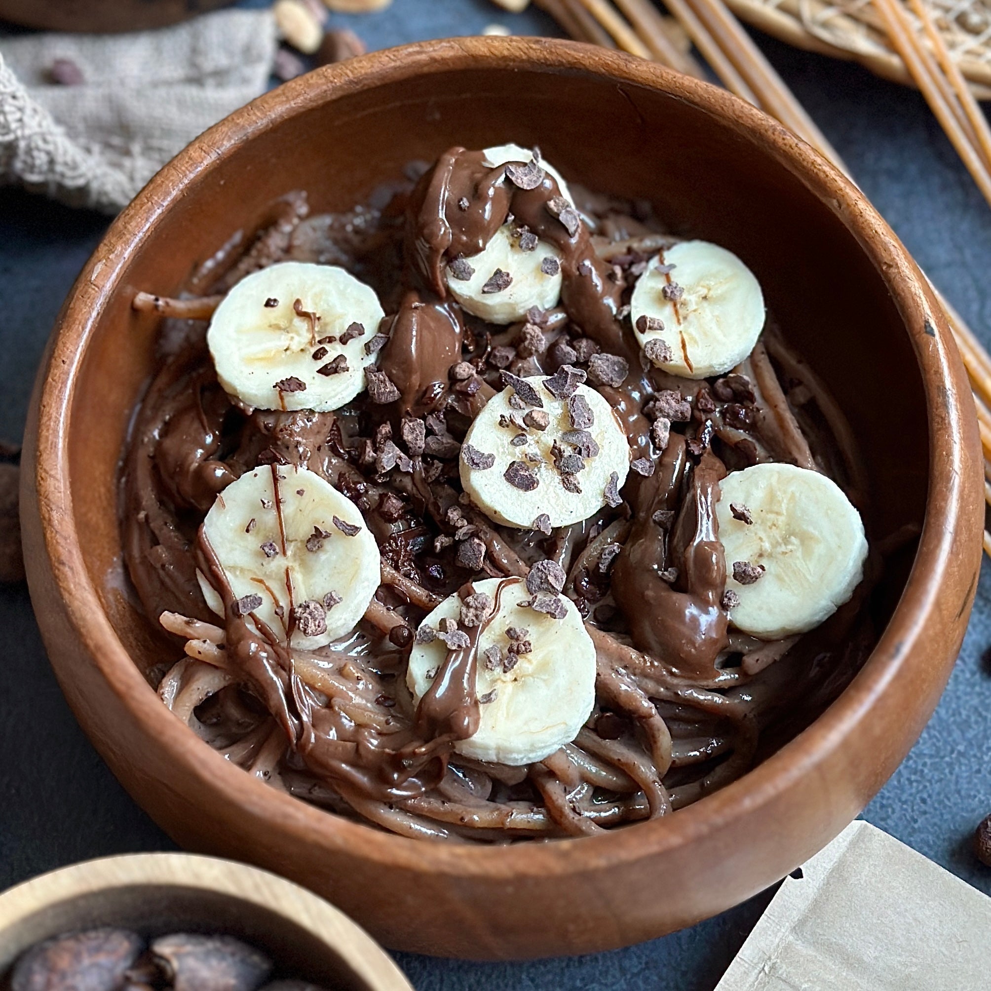 Schoko-Bananen Spaghetti mit cremiger Schoko-Protein-Sauce und frischen Bananenscheiben auf einem Teller angerichtet.
