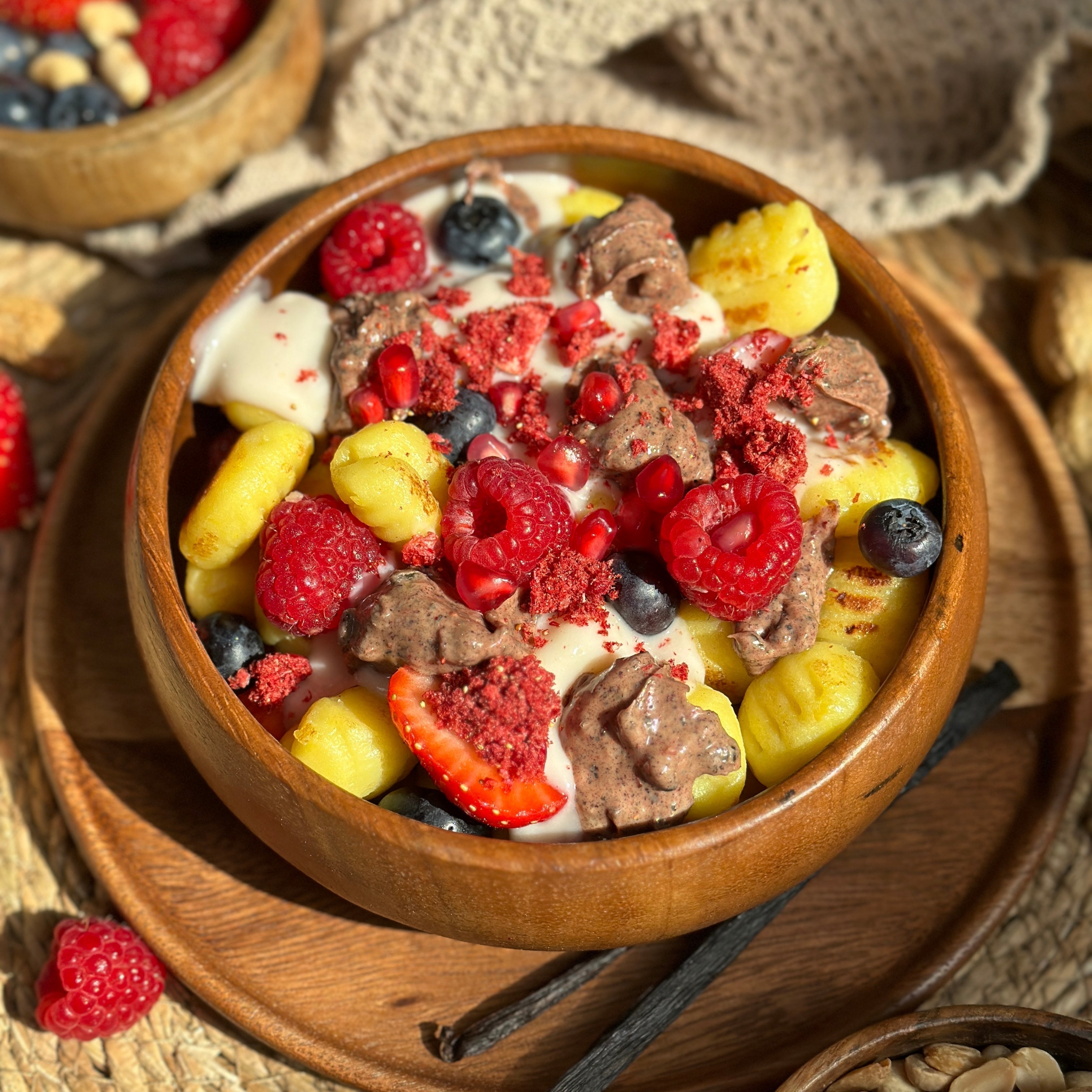 Süße Beeren-Gnocchi mit cremiger Vanillesoße, frischen Beeren und Protein Spread als Topping in einer weißen Schale angerichtet.
